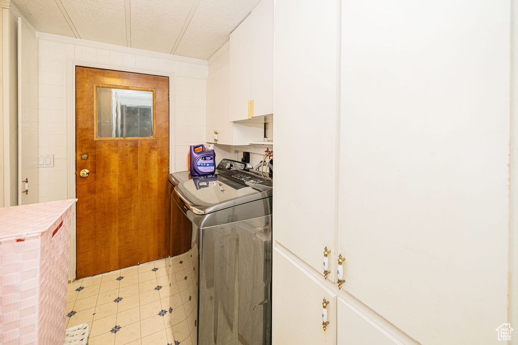 Laundry room featuring cabinet space, washing machine and dryer, and light tile patterned floors
