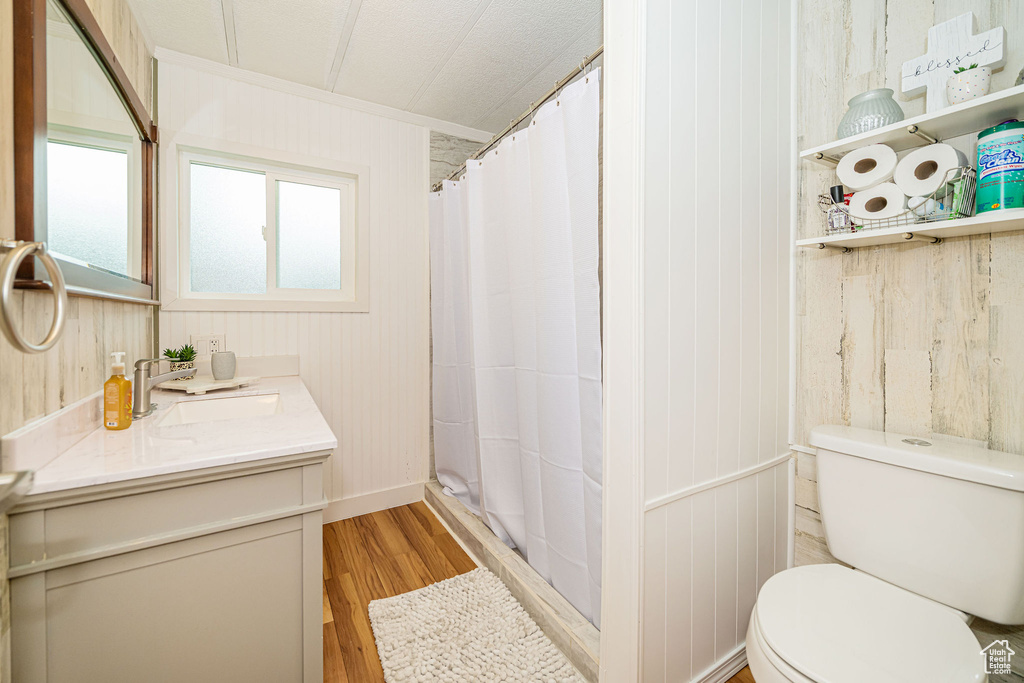 Bathroom featuring wood finished floors, toilet, vanity, ornamental molding, and wood walls