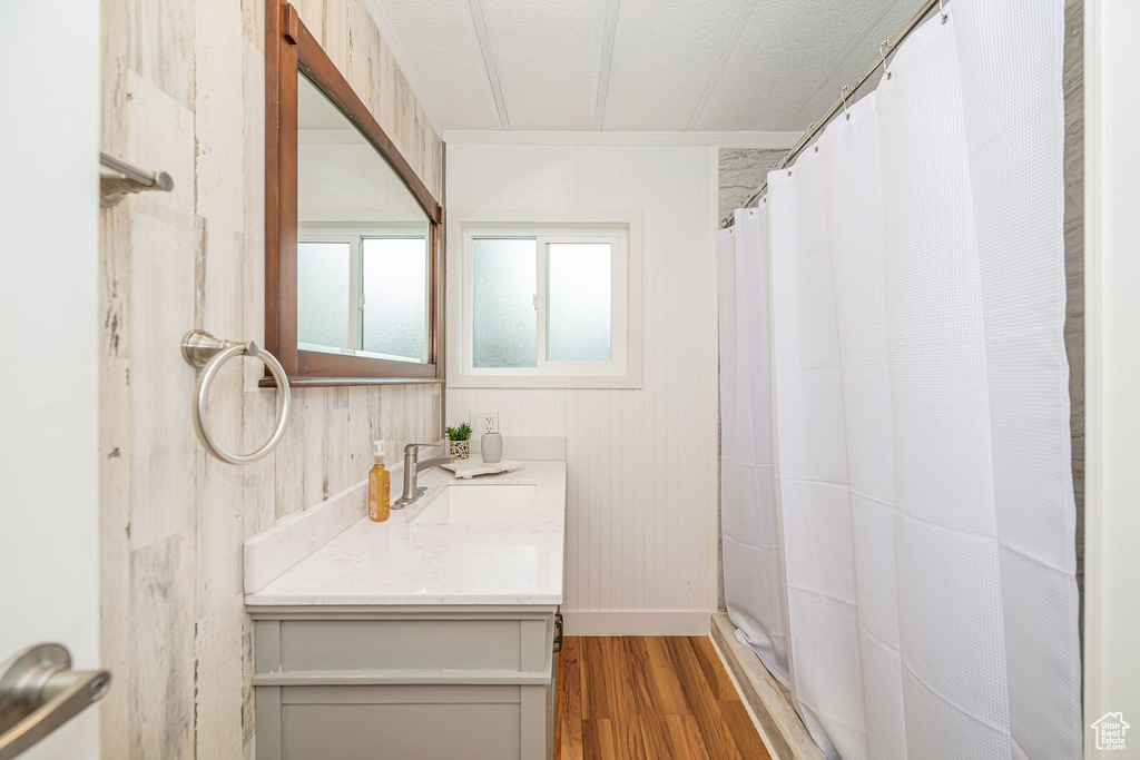 Full bath with wood finished floors, vanity, ornamental molding, baseboards, and wood walls