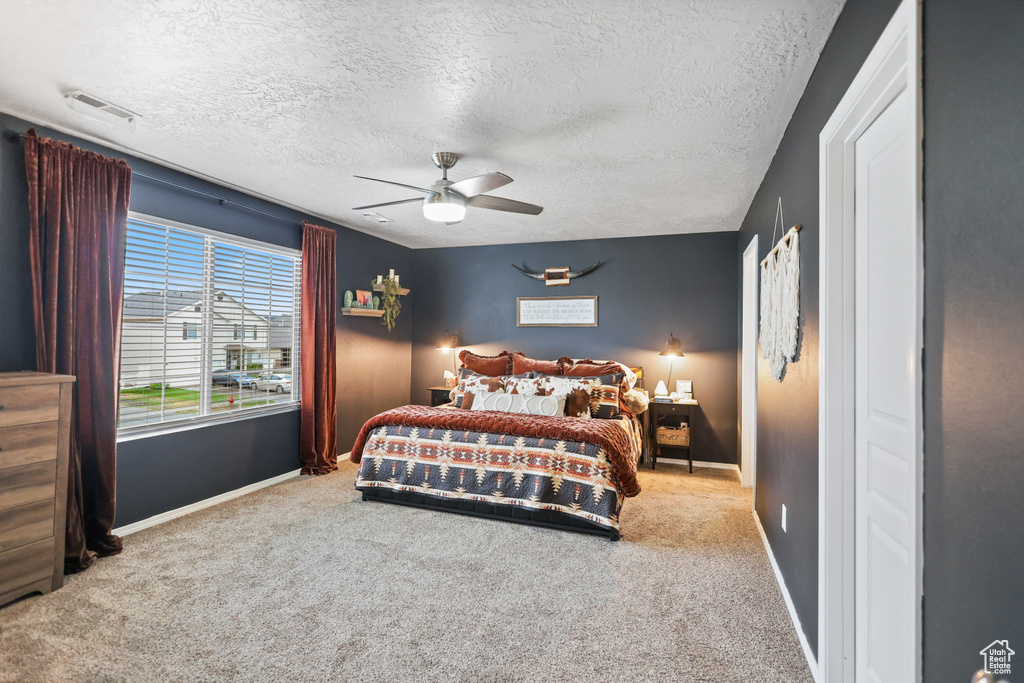 Bedroom featuring carpet floors, baseboards, a textured ceiling, and ceiling fan