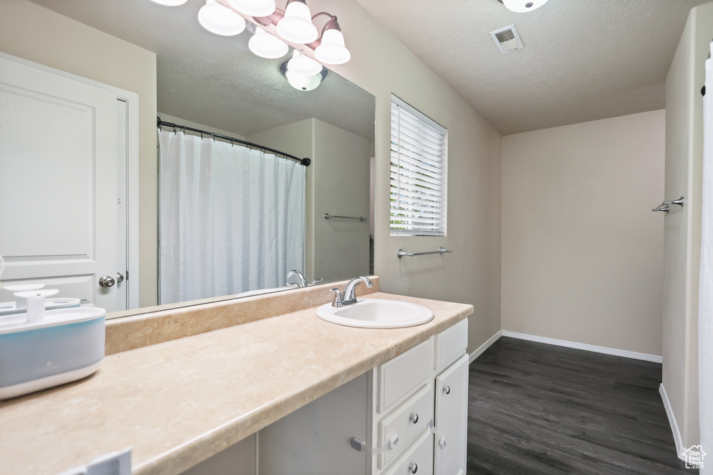 Full bath with baseboards, wood finished floors, a textured ceiling, and vanity
