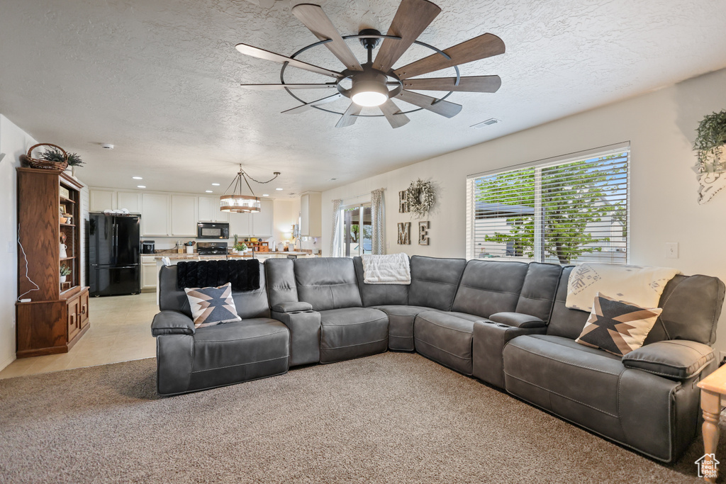 Living room with a chandelier, ceiling fan, a textured ceiling, and recessed lighting