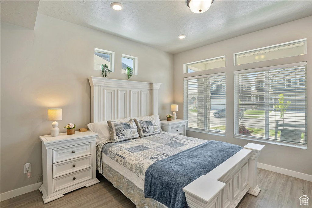 Bedroom with baseboards, light wood finished floors, a textured ceiling, and recessed lighting