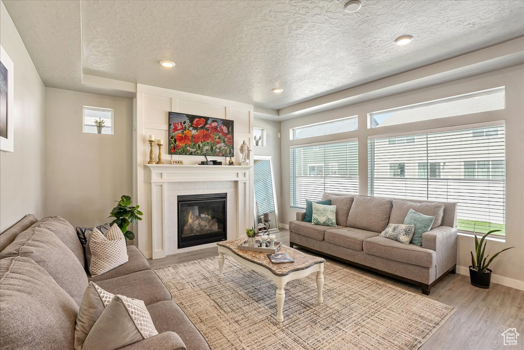 Living area featuring plenty of natural light, light wood finished floors, a textured ceiling, baseboards, and recessed lighting
