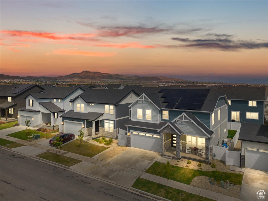 Traditional-style house with an attached garage, driveway, fence, stone siding, and roof mounted solar panels