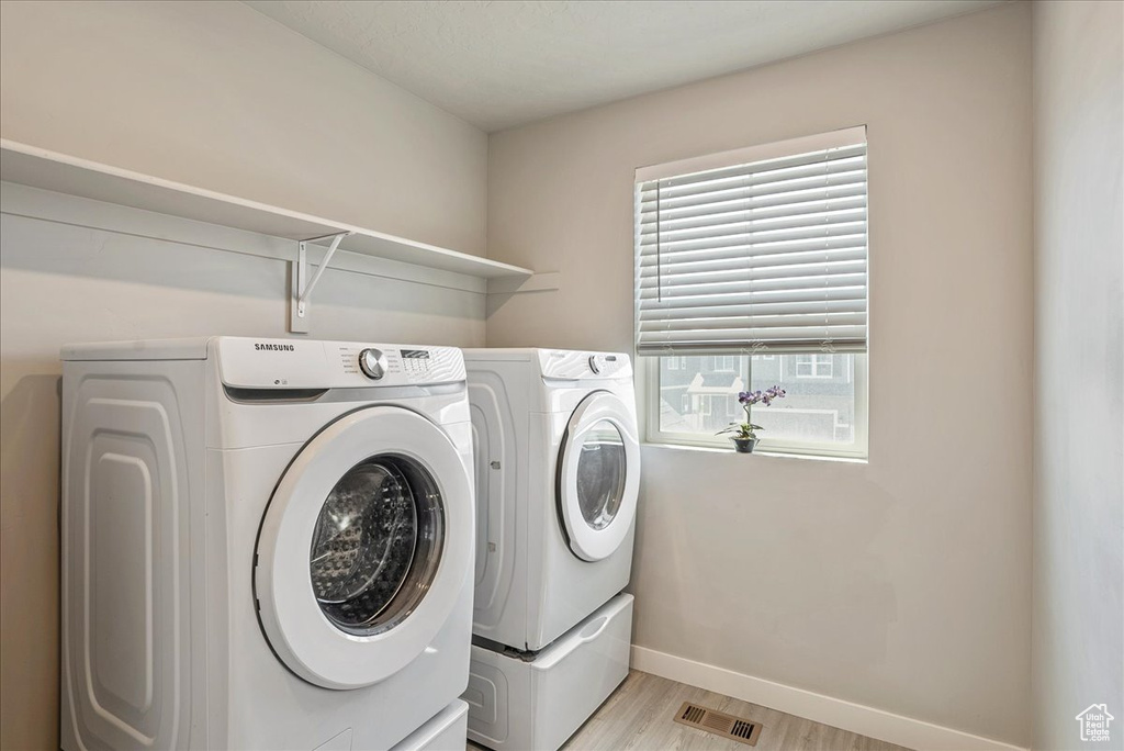 Laundry area with washing machine and dryer, light wood-type flooring, and baseboards