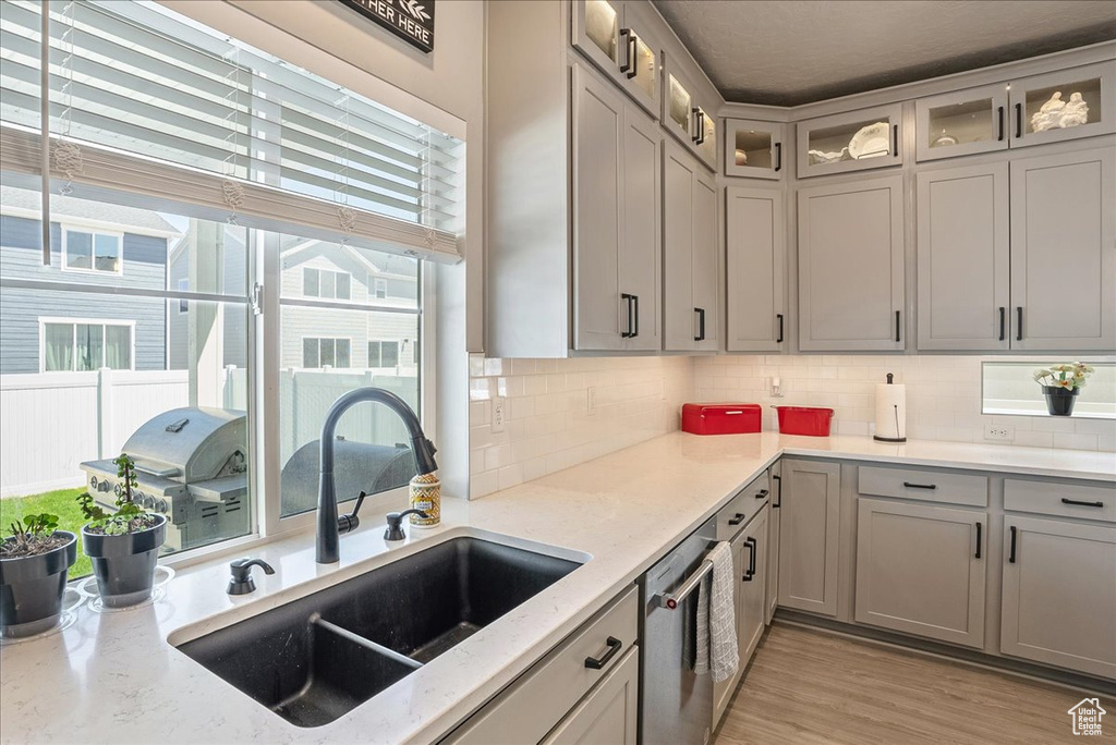 Kitchen featuring a sink, stainless steel dishwasher, healthy amount of natural light, and tasteful backsplash