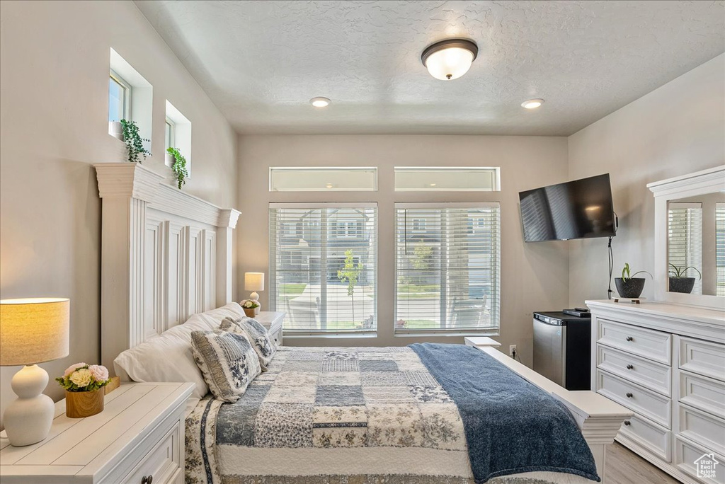 Bedroom with a textured ceiling, fridge, recessed lighting, and light wood finished floors