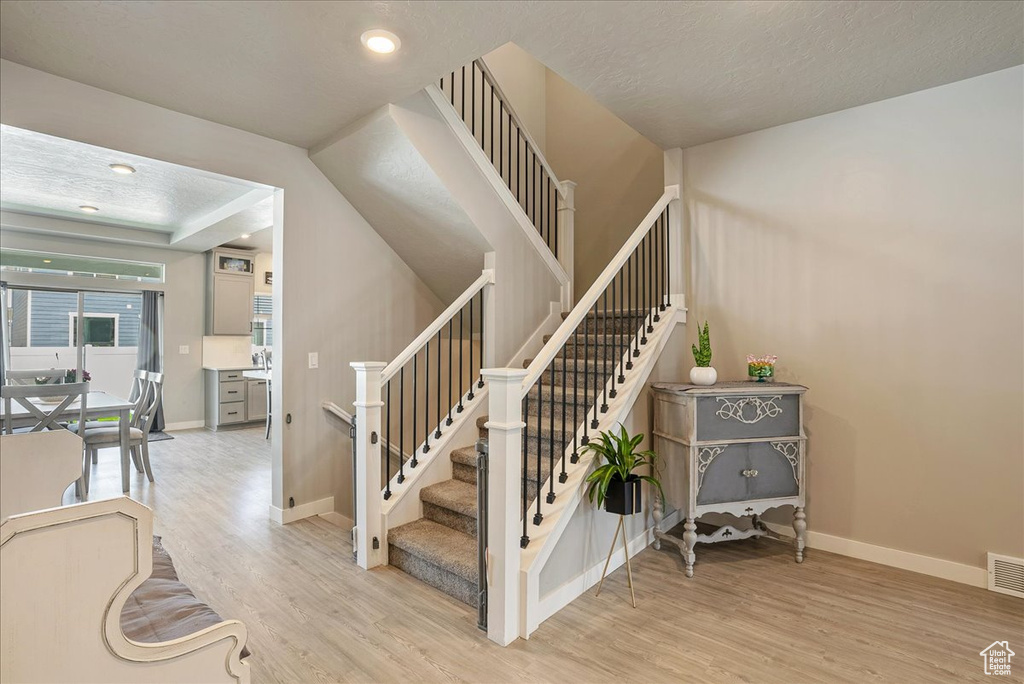 Stairway with wood finished floors, baseboards, and recessed lighting