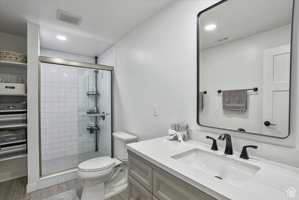 Bathroom featuring a shower stall, toilet, vanity, and wood finished floors