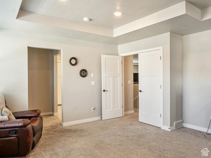 Sitting room with a tray ceiling, light colored carpet, baseboards, a textured ceiling, and recessed lighting