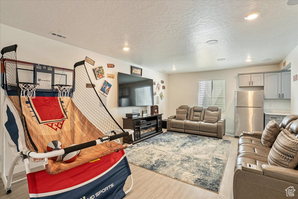 Living room with wood finished floors, a textured ceiling, recessed lighting, and baseboards