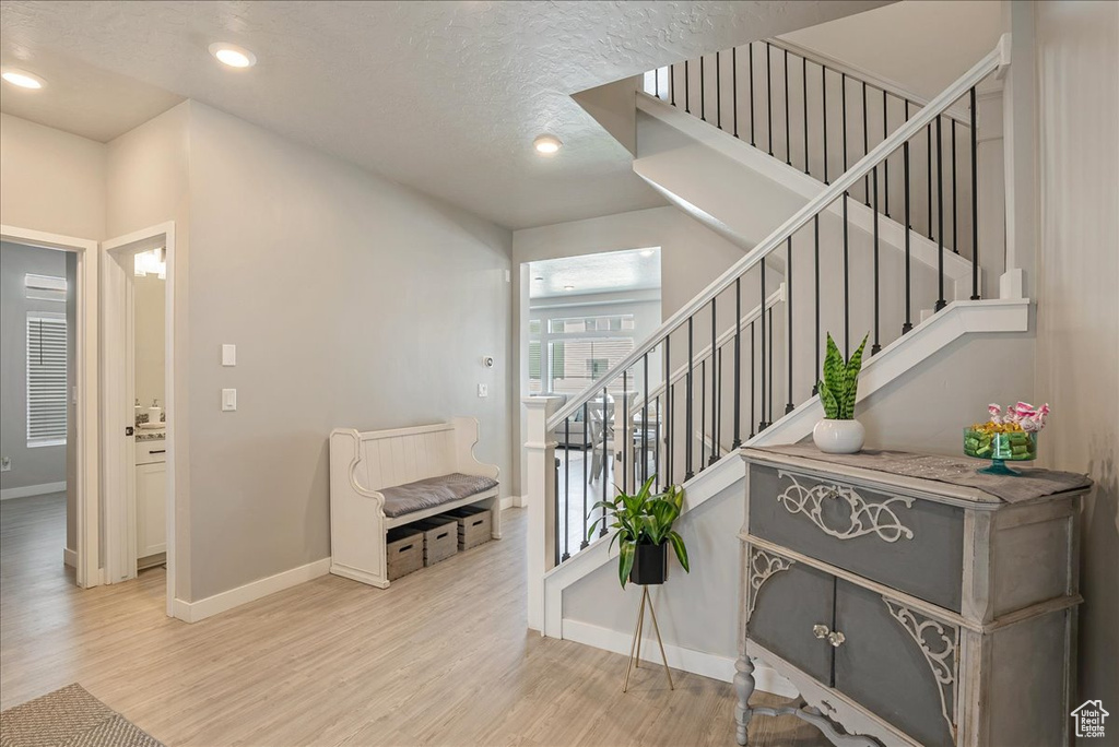 Stairway with wood finished floors, baseboards, recessed lighting, and a textured ceiling