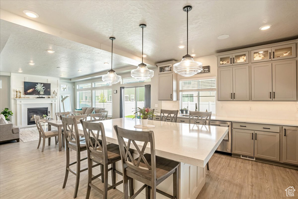 Kitchen with dishwasher, light wood-type flooring, open floor plan, a kitchen island, and a textured ceiling