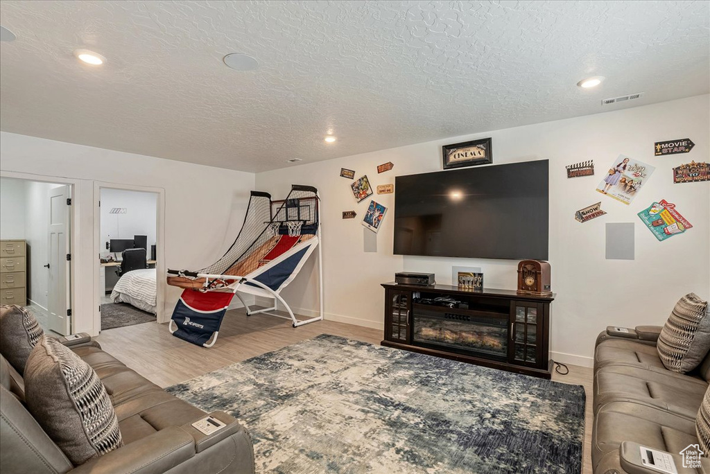 Living area featuring wood finished floors, baseboards, recessed lighting, and a textured ceiling