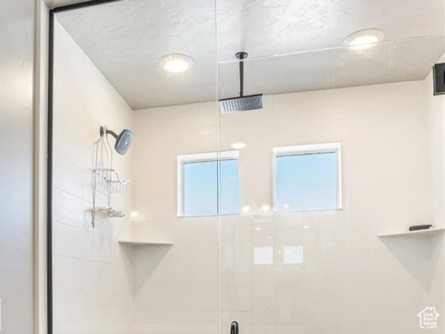 Full bathroom featuring a stall shower, a textured ceiling, baseboards, and tile patterned flooring