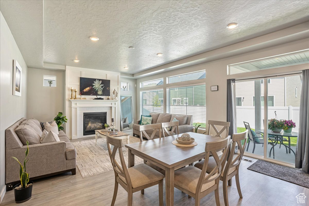 Dining room with a textured ceiling, light wood finished floors, and a large fireplace