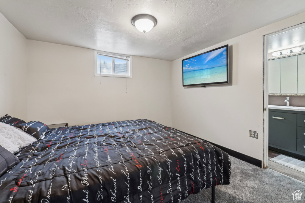 Bedroom featuring carpet floors, baseboards, a textured ceiling, and a sink