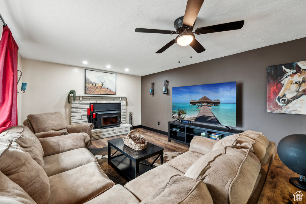 Living room with ceiling fan, wood finished floors, recessed lighting, a stone fireplace, and baseboards