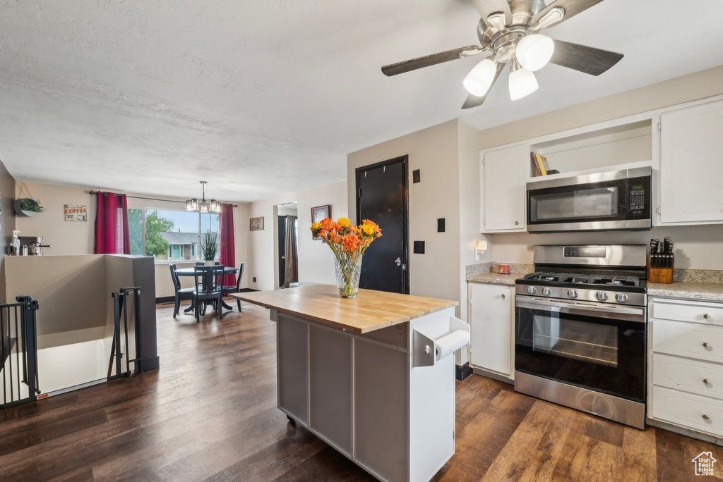 Kitchen featuring stainless steel appliances, wood counters, white cabinetry, a chandelier, and dark wood-type flooring