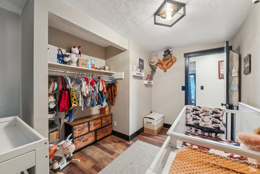 Bedroom with wood finished floors, a textured ceiling, and baseboards