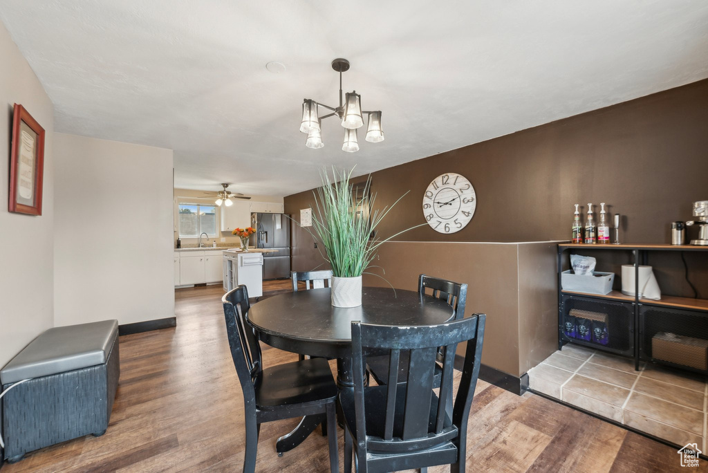 Dining area with wood finished floors, a chandelier, a ceiling fan, and baseboards