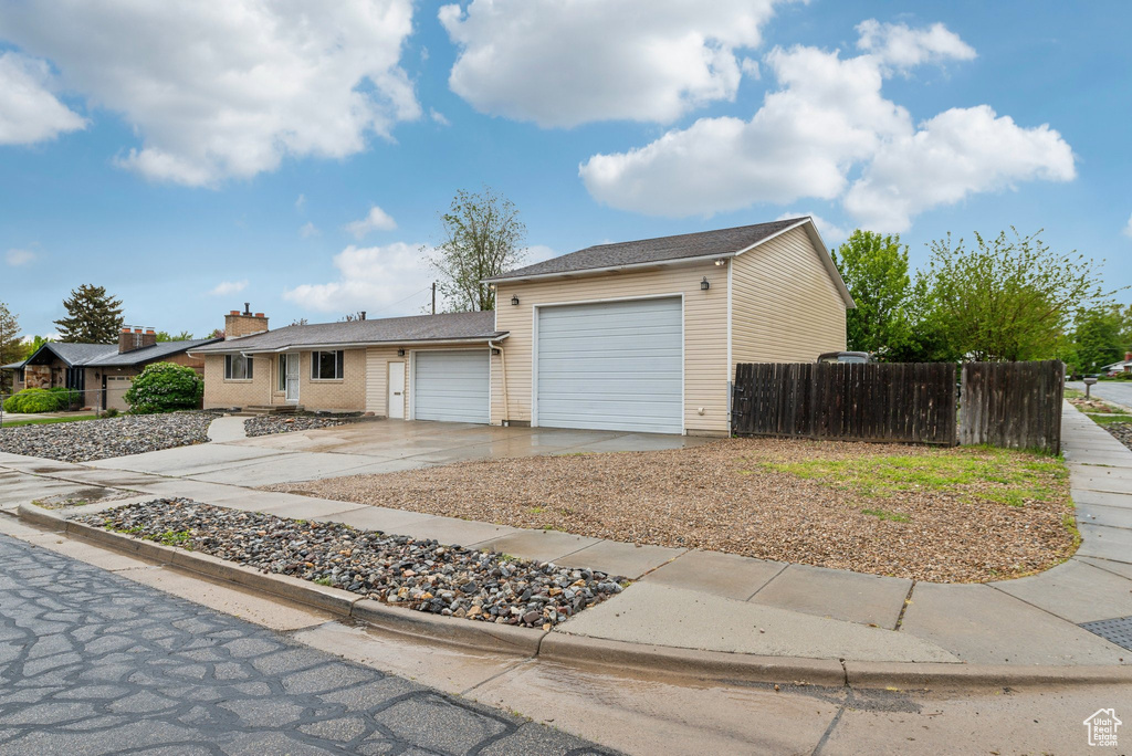 Ranch-style house with a garage, fence, and concrete driveway