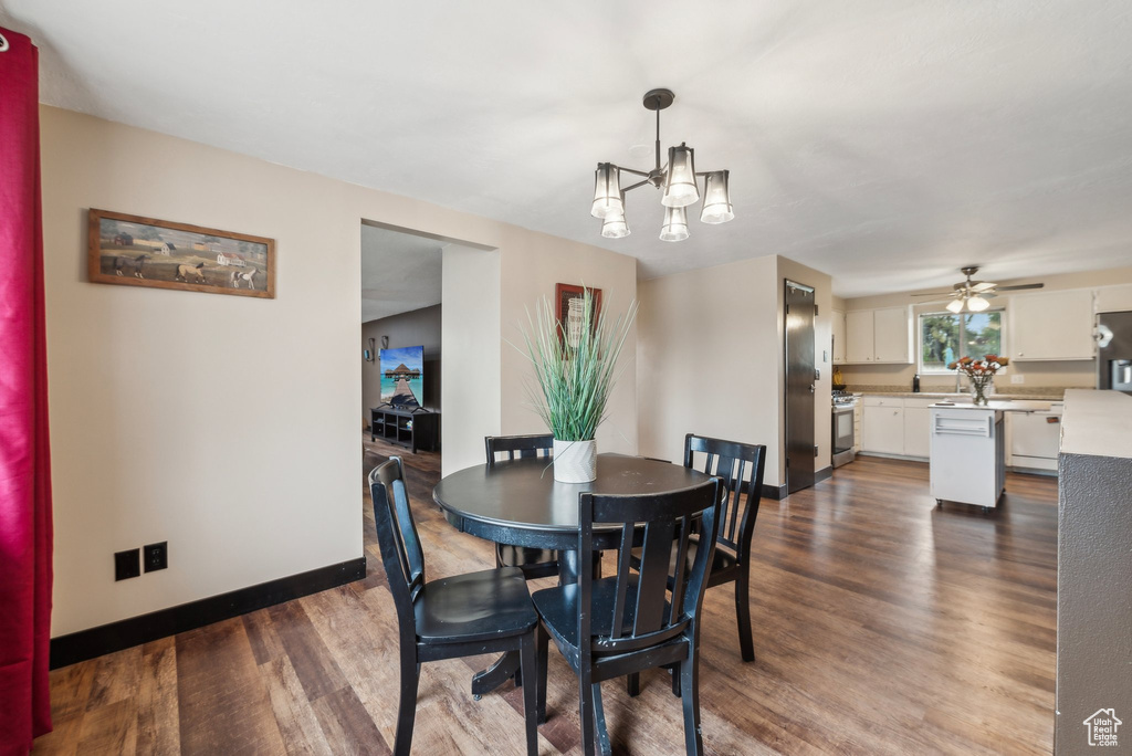 Dining area with dark wood finished floors, baseboards, a chandelier, and a ceiling fan