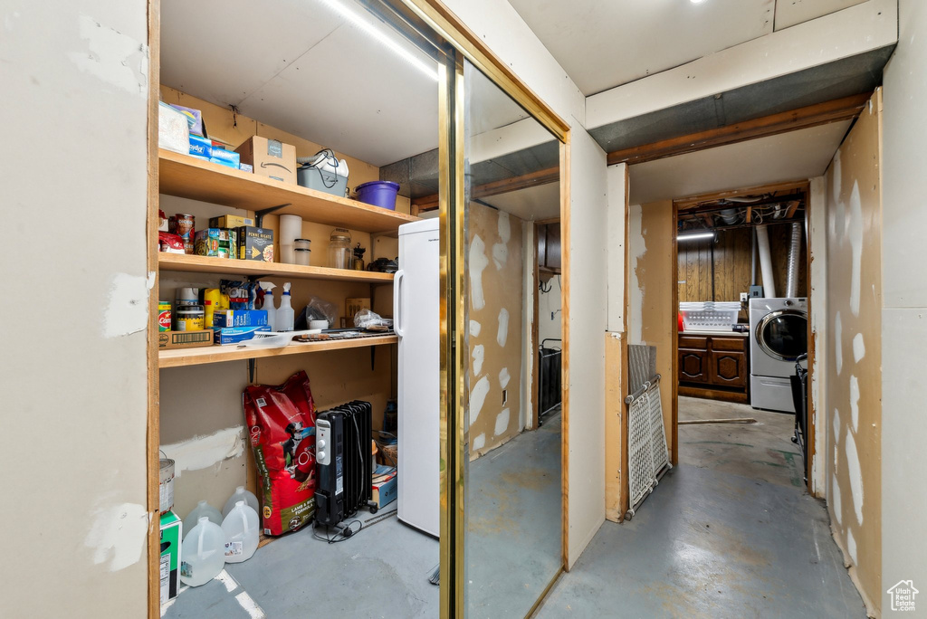 Unfinished below grade area featuring washer / clothes dryer and freestanding refrigerator