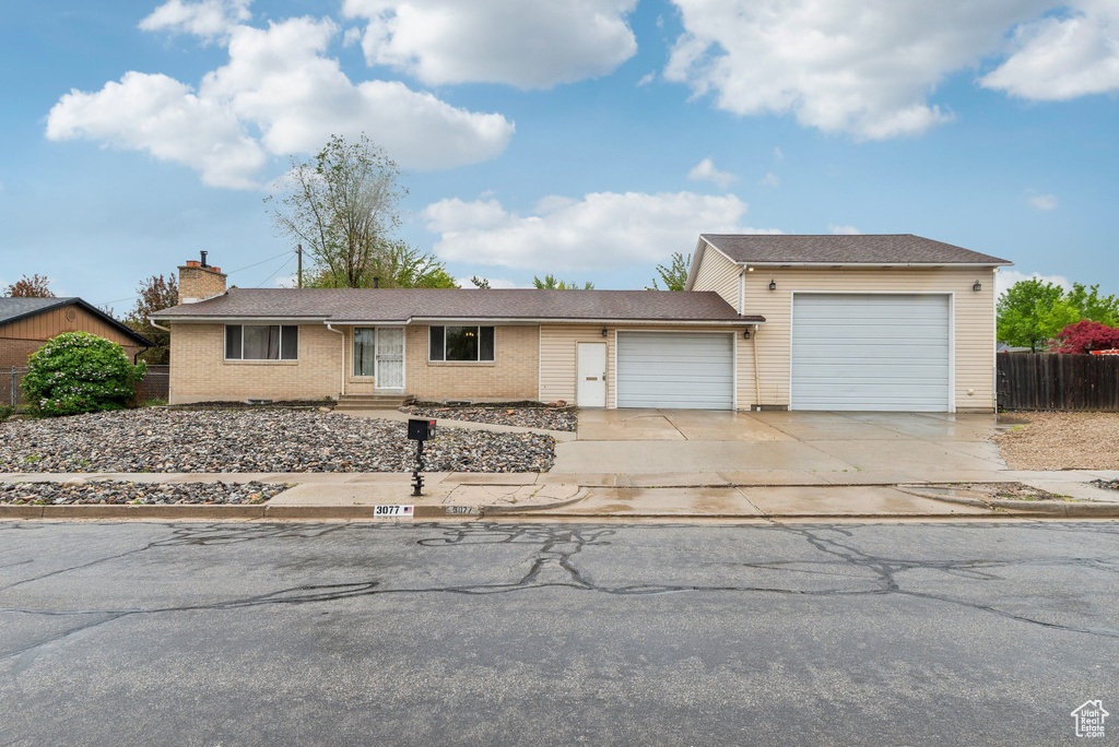 Ranch-style home with a garage, concrete driveway, fence, a chimney, and brick siding