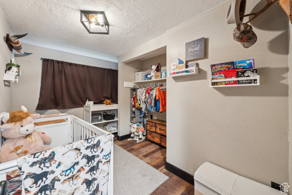 Bedroom with a textured ceiling, wood finished floors, a closet, and baseboards