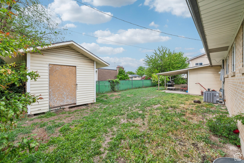 View of yard featuring a storage shed, a patio area, central AC, and an outdoor structure