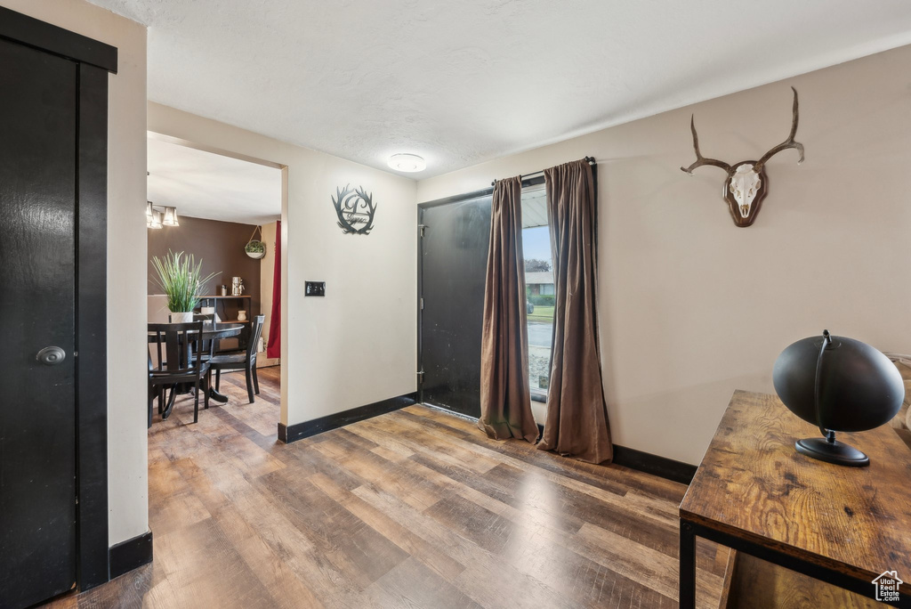 Foyer with wood finished floors, baseboards, and a chandelier