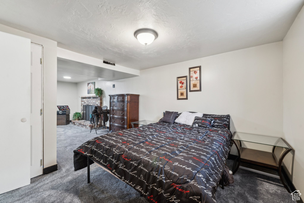 Bedroom with carpet floors, a brick fireplace, and a textured ceiling