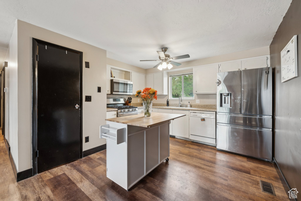Kitchen featuring stainless steel appliances, white cabinets, a ceiling fan, and dark wood-style flooring