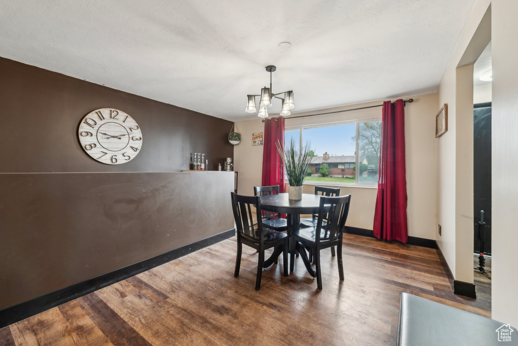 Dining space with wood finished floors, a chandelier, and baseboards