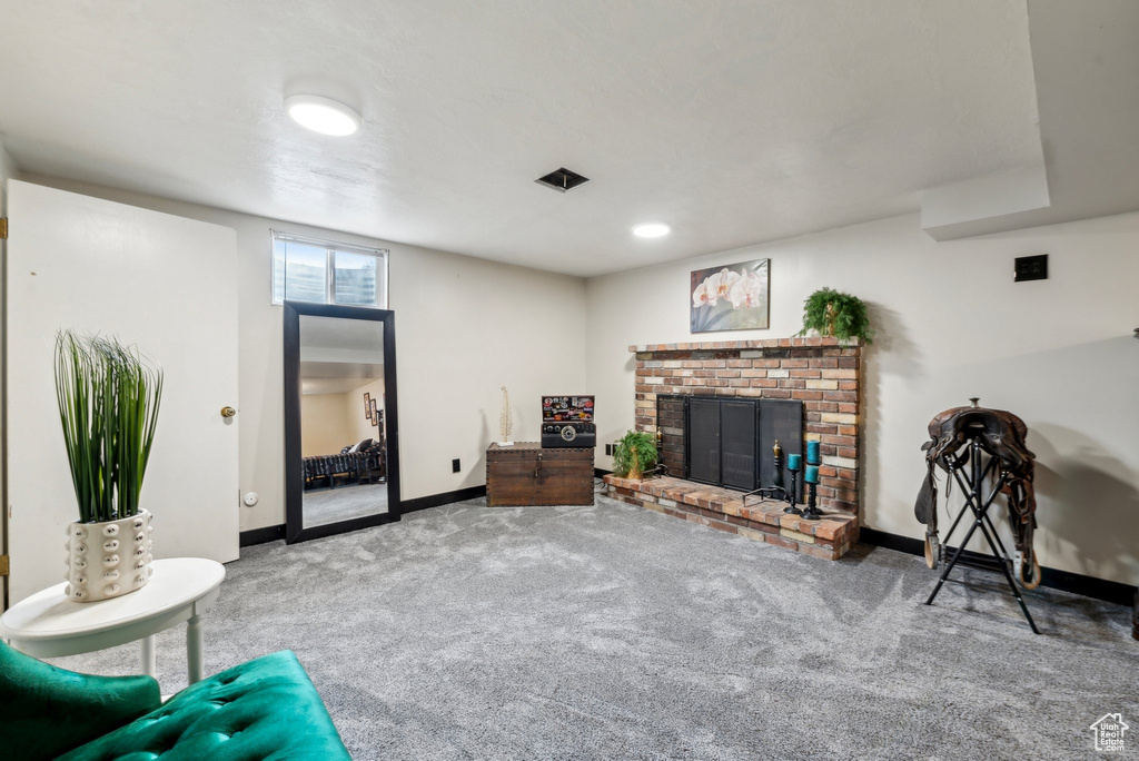 Living room featuring carpet flooring, baseboards, and a brick fireplace
