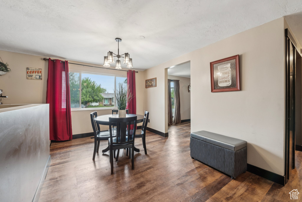Dining area with healthy amount of natural light, a chandelier, wood finished floors, and baseboards