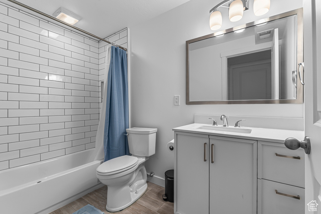 Bathroom featuring toilet, wood finished floors, vanity, and shower / bath combo