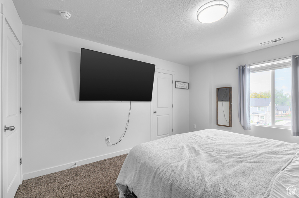 Carpeted bedroom with a textured ceiling and baseboards