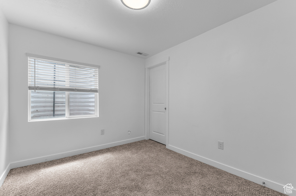 Spare room featuring carpet flooring and baseboards
