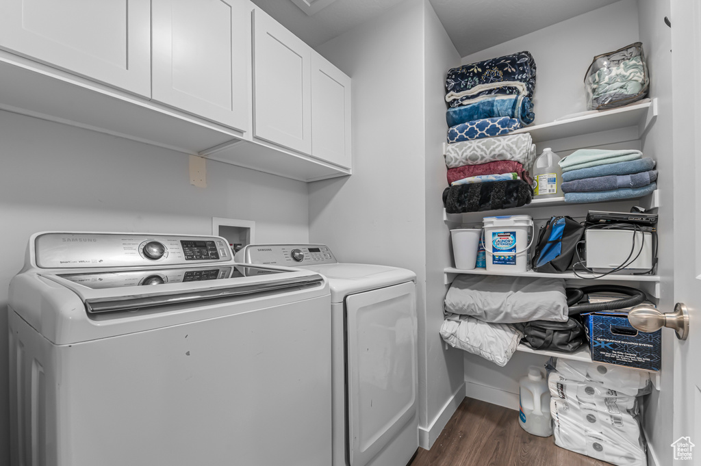 Washroom with washer and clothes dryer, cabinet space, dark wood-style flooring, and baseboards