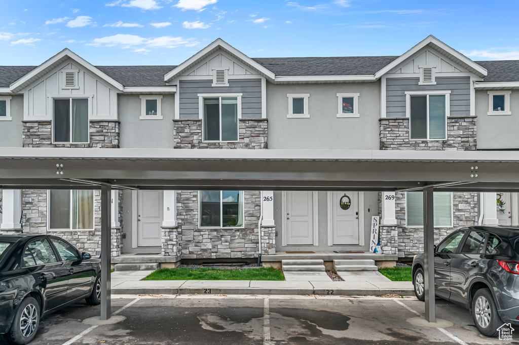 View of property featuring stone siding, covered parking, and board and batten siding