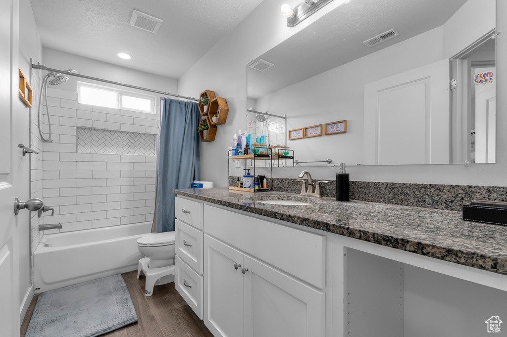 Full bathroom with wood finished floors, vanity, toilet, and shower / bath combo