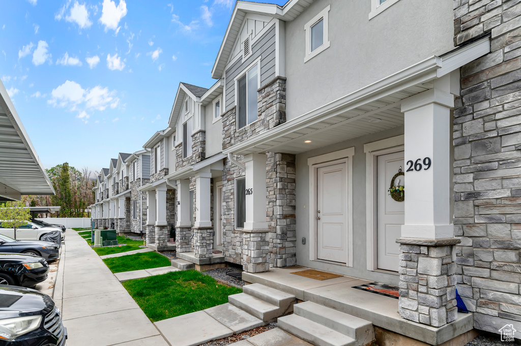 Doorway to property featuring stone siding, stucco siding, and a residential view