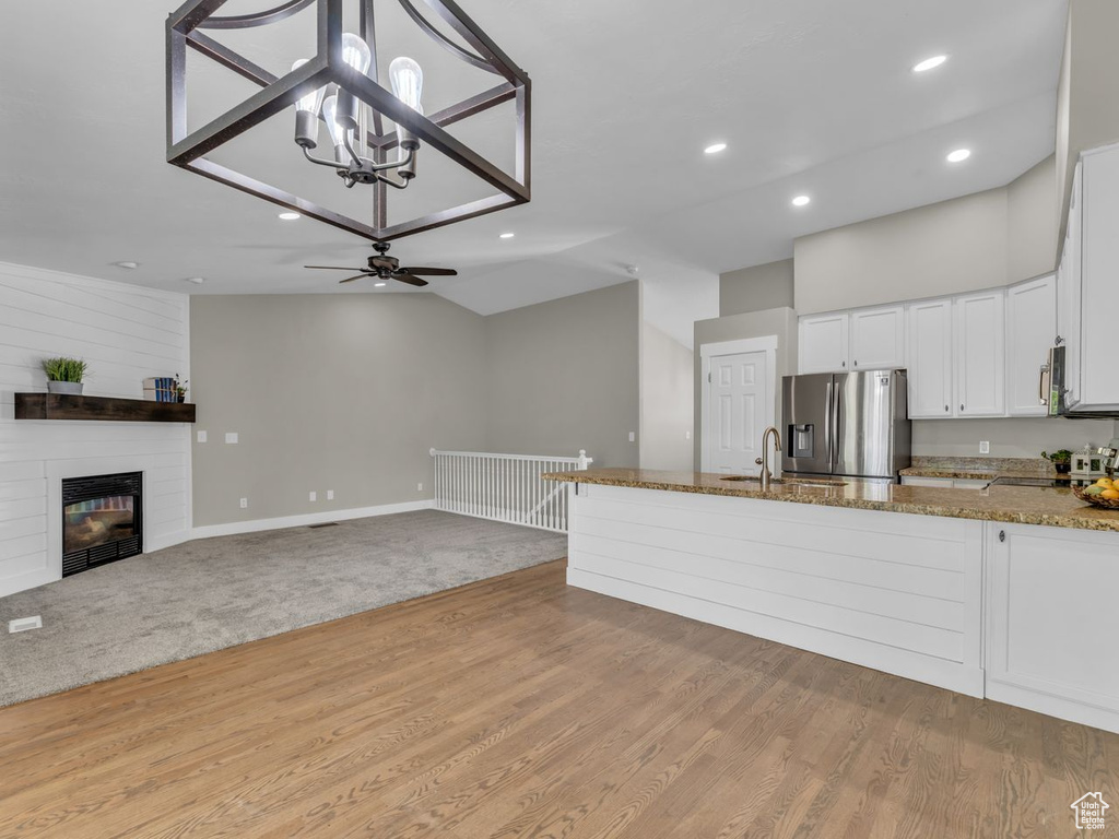 Kitchen with a peninsula, a sink, stone countertops, stainless steel appliances, and white cabinets