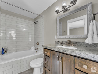 Bathroom featuring tiled shower / bath combo, vanity, and toilet