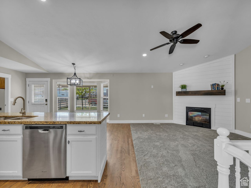 Kitchen with lofted ceiling, dishwasher, a sink, open floor plan, and a large fireplace