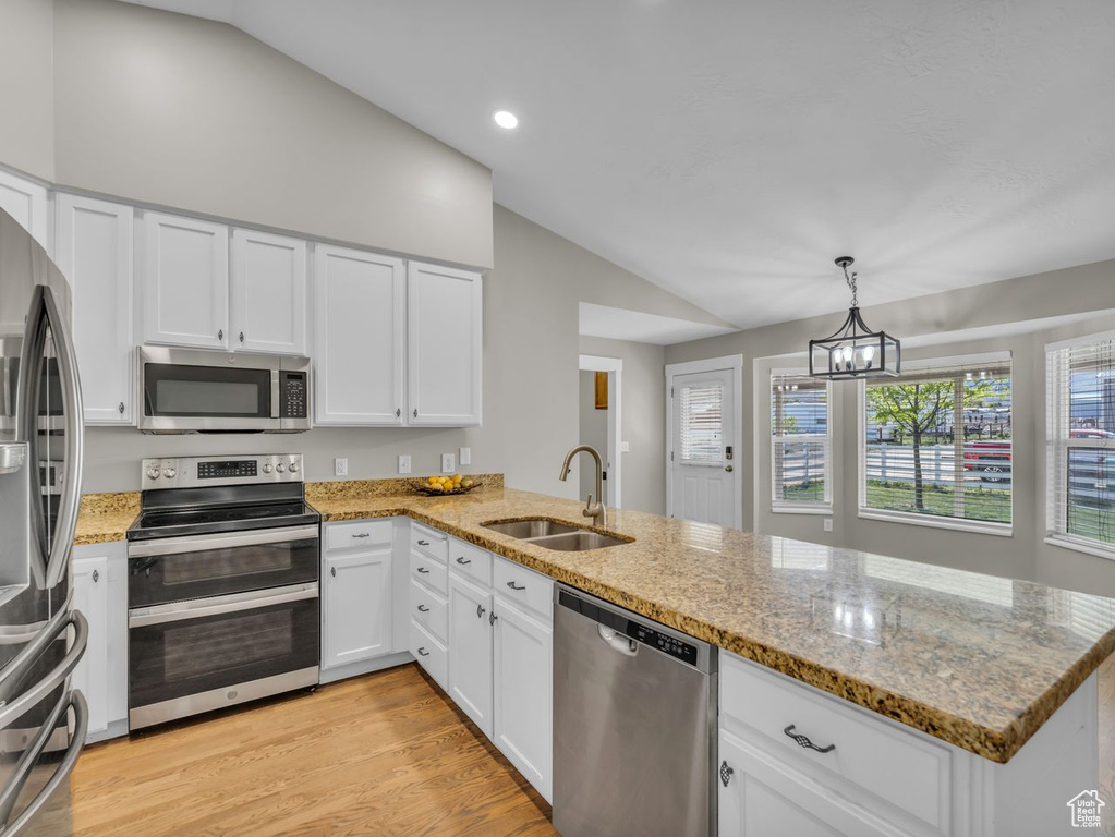 Kitchen with a peninsula, a sink, stainless steel appliances, a wealth of natural light, and lofted ceiling
