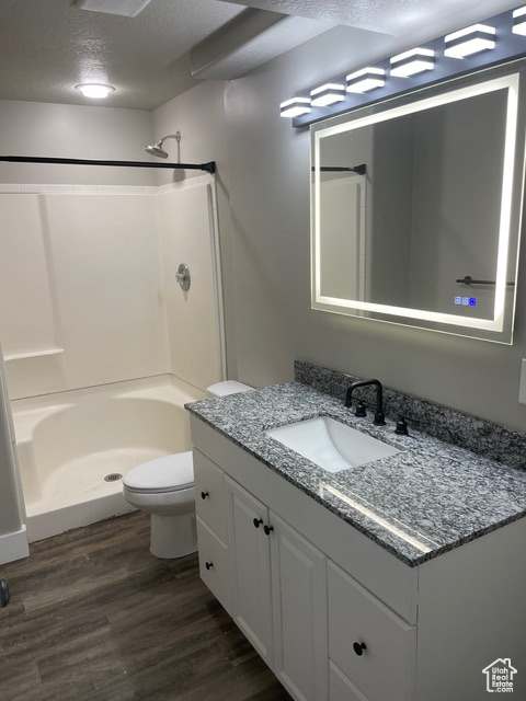 Bathroom featuring walk in shower, vanity, a textured ceiling, and wood finished floors